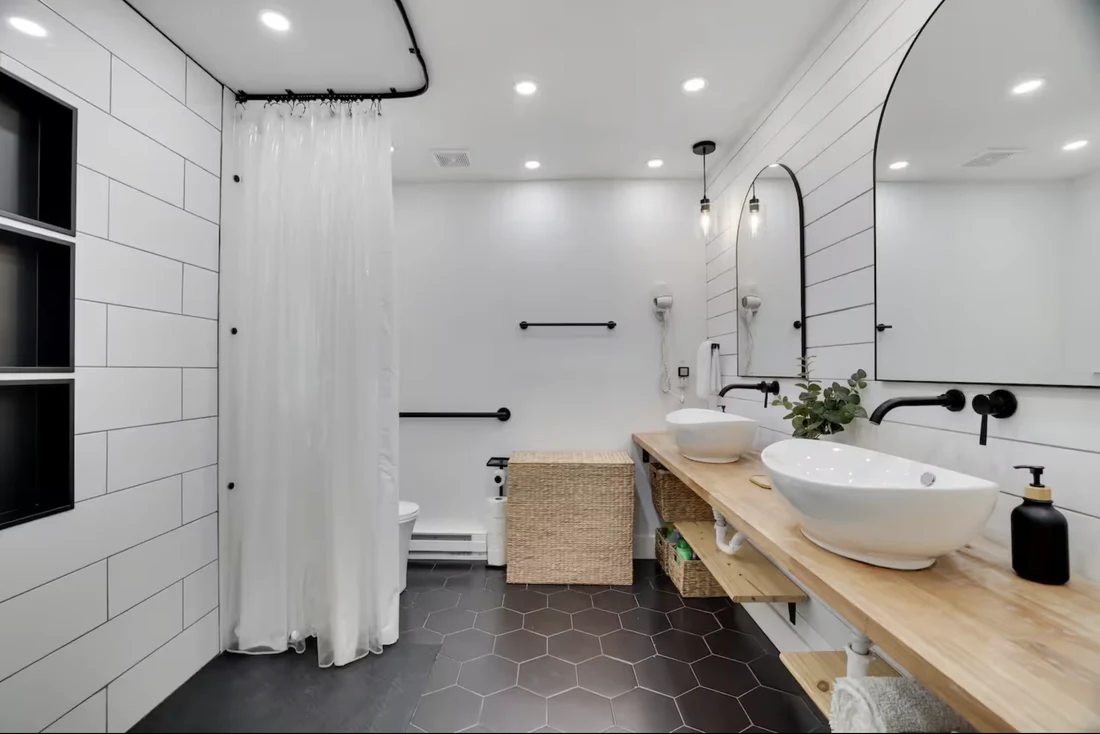 Accessible bathroom with a roll-in shower, black grab bars and a wood vanity