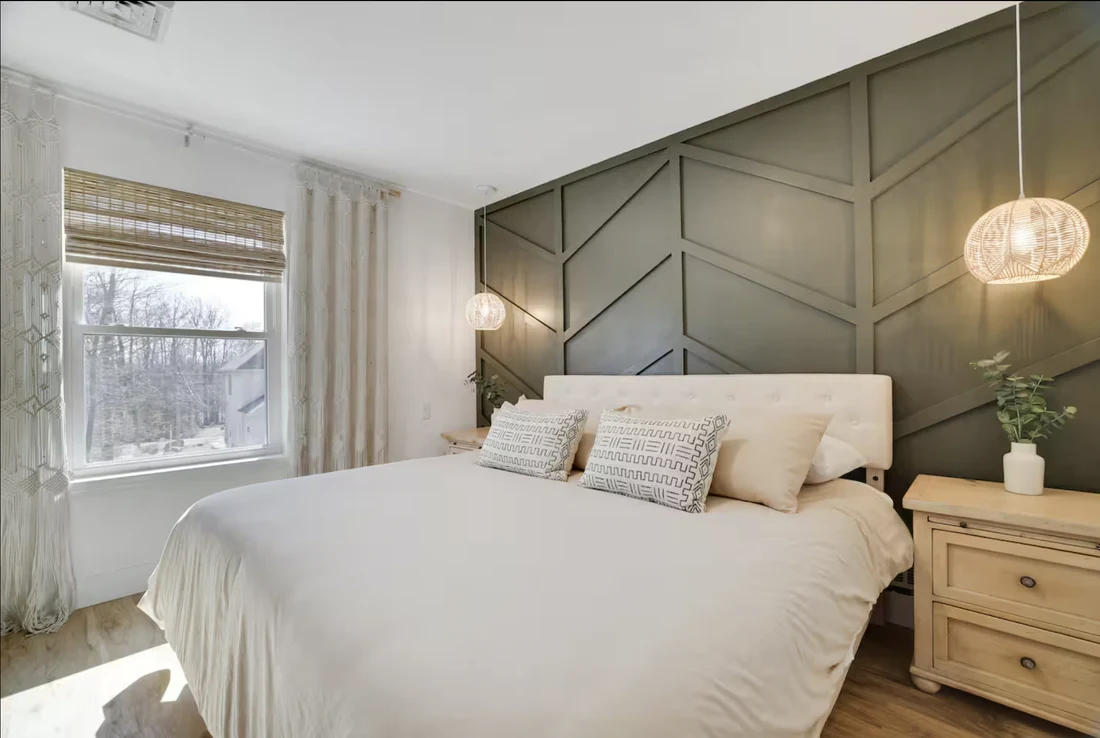 Bedroom with a dark green geometric board-and-batten wall and pendant lights