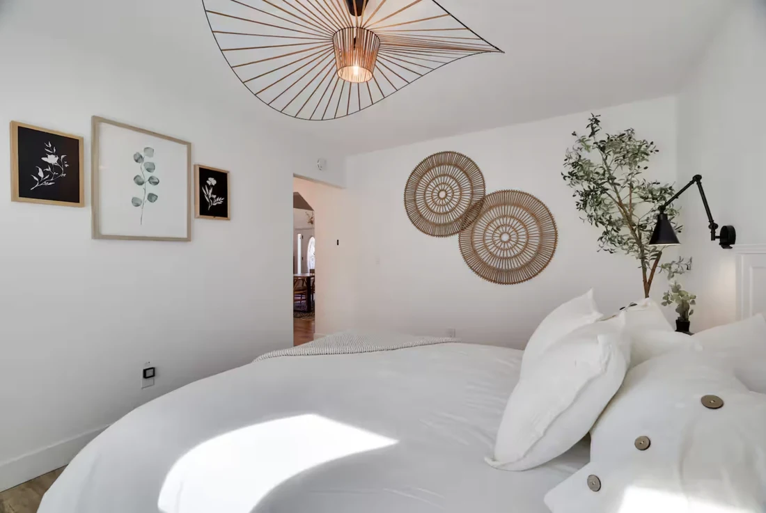 Guest bedroom at Villa Vincente with a round bed, woven wall art and a sculptural pendant light